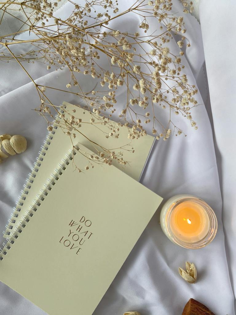 About Dream Life Connection 2 Top view composition of white spiral copybooks with inscription Do What You Want placed on white cloth with burning candle and tender flower